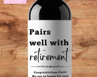 May include: A white wine bottle label with black text that reads "Pairs well with retirement". Below the text is a decorative line and the words "Congratulations Patti! We are so happy for you!"