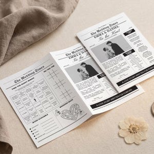 Op de afbeelding: Een trouw-krant met de kop "The Wedding Times" en de namen "Emma & Daniel". De krant bevat foto's van het paar, spelletjes en de zin "A Love Story Written For Forever". Een gedroogde bloem en een zegel zijn ook aanwezig.