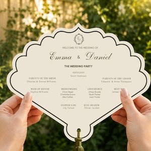 Puede incluir: Un programa de boda en forma de abanico de color crema con un borde festoneado marrón oscuro y una borla en la parte inferior. El texto dice: Welcome to the wedding of Emma & Daniel, The Wedding Party, Officiant Scott Andrews, y lista los nombres.