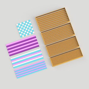 May include: Four gold-colored cookie cutters in the shape of a rectangle with horizontal lines. There are also three cookie cutters in the shape of a rectangle with different colored stripes. One cookie cutter is a checkered pattern in blue and white.