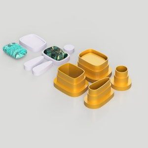 Op de afbeelding: Een set witte en gouden geometrische nestdozen. De dozen zijn gemaakt van een glad, hard materiaal en hebben verschillende vormen en maten. De dozen zijn in een verspringend patroon gerangschikt, met de grootste doos onderaan en de kleinste doos bovenaan.