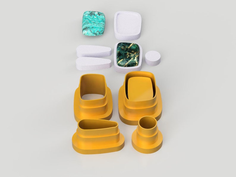 Op de afbeelding: Een set van zeven gele plastic koekjesvormen in verschillende vormen, waaronder een rechthoek, een ovaal en een cirkel. De vormen zijn op elkaar gestapeld.