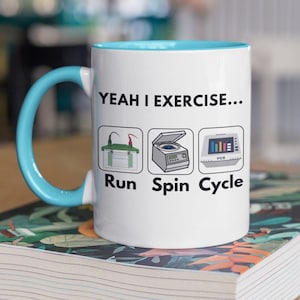 May include: White ceramic mug with a light blue rim and handle. The mug has a black graphic that says "Yeah I exercise..." with three illustrations of lab equipment and the words "Run", "Spin", and "Cycle".