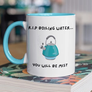 May include: White ceramic mug with a blue rim and handle. The mug features a cartoon illustration of a blue kettle with steam coming out of the spout. The text on the mug reads "R.I.P. Boiling Water... You Will Be Mist."