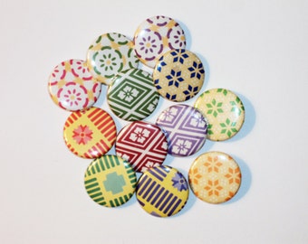 Puede incluir: Una colección de botones coloridos con diseños. Los botones presentan varios diseños geométricos y florales en tonos de amarillo, verde, rojo, morado y azul. Los botones redondos tienen un acabado brillante, perfectos para manualidades o para decorar ropa.