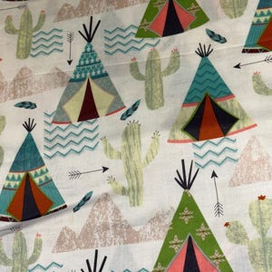 May include: White fabric with a repeating pattern of teepees, cacti, mountains, arrows, and feathers. The teepees are in shades of green, teal, and brown, with pink and black accents. The cacti are light green.