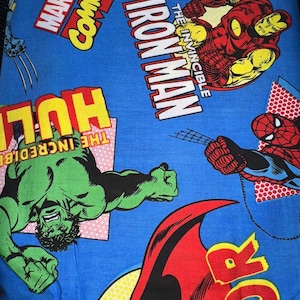 May include: Blue fabric featuring Marvel Comics characters including Iron Man, Hulk, and Spider-Man. The fabric has comic book style graphics with bold colors and text. The Marvel Comics logo is also visible.