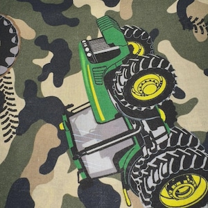 May include: Camouflage fabric featuring a green and yellow tractor design. The tractor has large black tires with yellow rims. The background is a classic camouflage pattern in shades of green, brown, and tan.