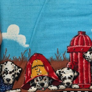 May include: Fabric with a blue sky background and white clouds. The fabric features Dalmatian puppies, a red fire hydrant, and a puppy wearing a fireman's hat. The hat has the word "Fireman" on it.