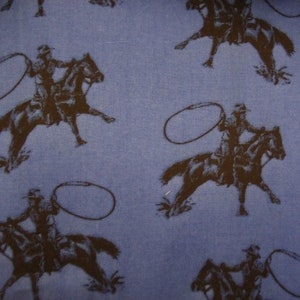 May include: Blue fabric with a repeating pattern of cowboys on horseback, each holding a lasso. The cowboys and horses are depicted in a dark brown color, creating a contrasting design against the blue background.