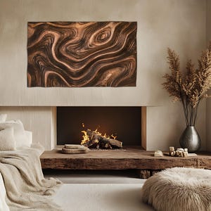 May include: A copper-toned wall art piece with a swirling, organic pattern hangs above a fireplace. The artwork's rich brown and bronze hues complement the warm tones of the room. The fireplace features a burning fire and a rustic wooden mantel.