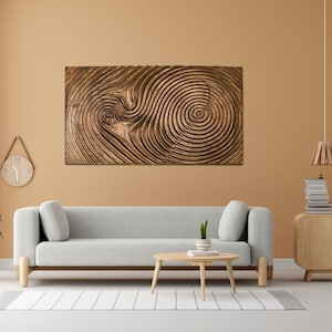 May include: A large, rectangular wooden wall art piece with a swirling, textured design in shades of brown. The artwork hangs above a gray sofa in a modern living room setting.
