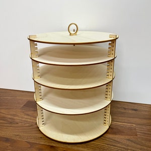 May include: A wooden rotating display stand with five circular shelves. The stand is made of light wood and has a simple design.