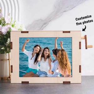 May include: A wooden picture frame with a light wood finish. The frame has a cutout for a photo and a small wooden knob on the side. The photo shows four people smiling and laughing on a boat. The text "Customize five photos" is visible in the top right corner of the image.