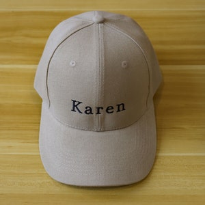 Puede incluir: Una gorra de béisbol beige con el nombre "Karen" bordado en negro en la parte delantera.