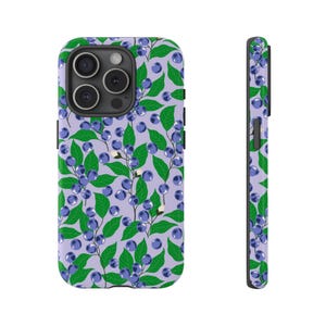 Könnte beinhalten: Eine lila Handyhülle mit einem Muster aus grünen Blättern und blauen Beeren. Die Hülle ist für ein Handy mit einer Dreifachkamera konzipiert.