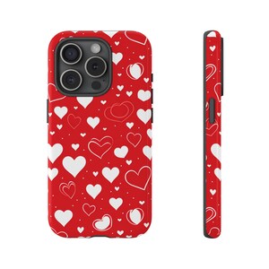 Könnte beinhalten: Eine rote Handyhülle mit einem weißen Herzmuster. Die Hülle ist für ein iPhone mit einer Kamerabuckel konzipiert.