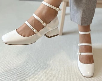Beyaz Rugan Tokalı Bant Detaylı Küt Burun Kadın Topuklu Ayakkabı. Küt Burnu ve Bant Detaylarıyla Farkını Ortaya Koyacak.