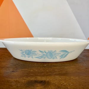 Peut inclure: Plat de service ovale blanc avec un motif floral bleu clair. Le plat a un bord légèrement évasé et est fait d'un matériau durable. Le motif floral présente des fleurs et des feuilles stylisées. Une pièce vintage pour servir des aliments.