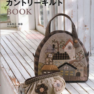 Puede incluir: Un bolso acolchado y un clutch a juego con un diseño de patchwork de casas y árboles. El bolso tiene un asa marrón y un cierre de botón. El clutch presenta aplicaciones florales. El libro tiene texto japonés.