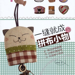 May include: A book cover with a brown and white cat keychain on the front. The book title is "One Stitch Makes It: Patchwork Small Things". The book cover also features a variety of colorful patchwork designs.