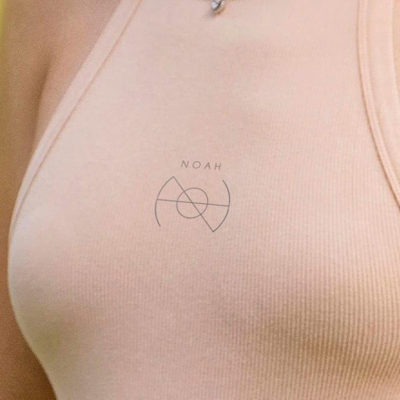 May include: A light peach-colored ribbed tank top with the word "NOAH" above a minimalist graphic. The graphic is a combination of geometric shapes, including a circle and triangles. The tank top is made of a soft, ribbed material.