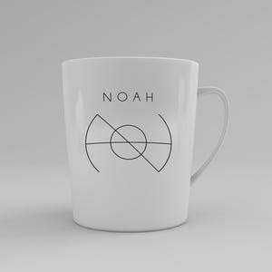 May include: White ceramic mug with the name "NOAH" printed in black, above a geometric design. The mug has a curved handle and a simple, modern aesthetic. The design is centered on the mug.