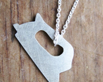 Könnte beinhalten: Eine silberne Kette mit einem Anhänger in Form eines Bügeleisens.