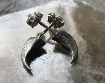 May include: A pair of silver claw-shaped earrings with a post and butterfly back.