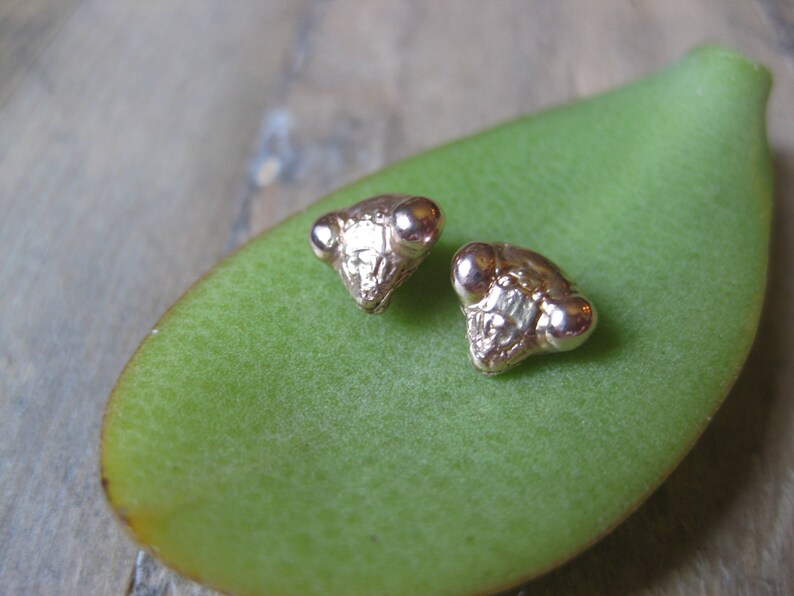 May include: A pair of gold-toned earrings shaped like the head of a praying mantis.