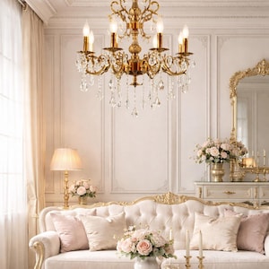 Puede incluir: Un salón lujoso con una lámpara de araña dorada, un sofá blanco con cojines rosas y una mesa de centro blanca. La habitación está decorada en un estilo clásico con detalles dorados y arreglos florales.