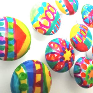 May include: A collection of vibrantly painted Easter eggs. Each egg features unique, colorful designs with bold patterns and bright hues, including blue, yellow, red, and green. The eggs are arranged against a white background, showcasing their artistic details.