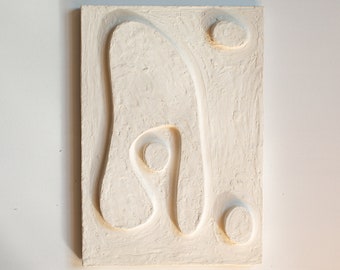 Può includere: Arte da parete astratto bianco con una superficie testurizzata e forme organiche in rilievo. Il pezzo ha un'estetica moderna e minimalista.