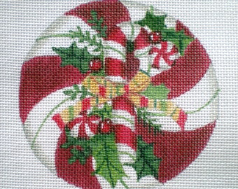 May include: A red and white candy cane ornament with green holly leaves and a yellow bow. The ornament is a traditional Christmas decoration.