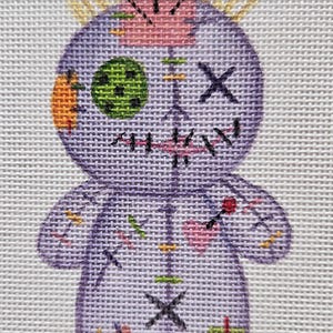May include: A purple voodoo doll with a yellow halo, red and green buttons, and a stitched X for eyes. The doll is decorated with various stitches and pins.