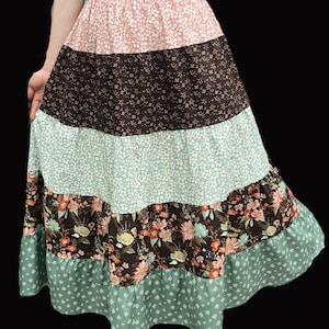 May include: A tiered skirt with a floral pattern in shades of pink, brown, and green. The skirt has a ruffled hem and a variety of floral prints. The skirt is made of a soft, flowing fabric.