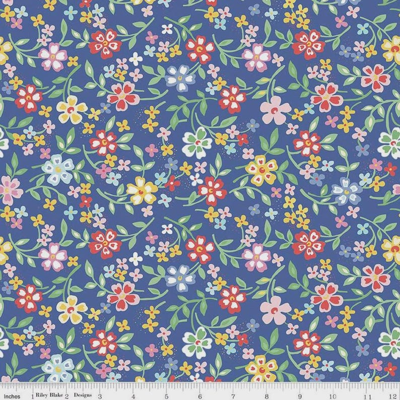 May include: A blue fabric with a floral pattern. The design features red, pink, yellow, and white flowers with green vines and leaves. The fabric is marked with inches.