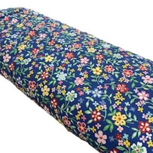 May include: A roll of fabric with a dark blue background and a colorful floral pattern. The flowers are in shades of red, yellow, pink, and white, with green leaves. The fabric is tightly rolled.