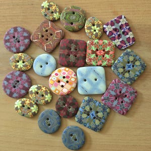 May include: A collection of assorted buttons in various shapes, including round, square, and rectangular forms. These buttons feature diverse patterns such as floral, geometric, and marbled designs in a wide array of colors like blue, green, red, and yellow.
