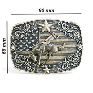 May include: A rectangular, antique-style belt buckle, 3.5 inches wide and 2.7 inches tall, with a detailed design. It features a cowboy riding a bucking bronco against a backdrop of the American flag, with star and scroll accents.