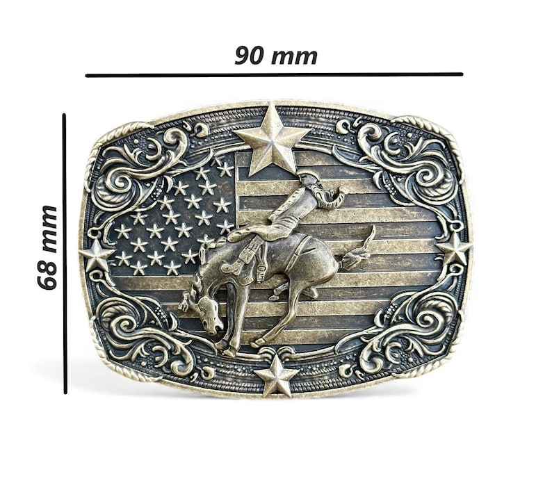May include: A rectangular, antique-style belt buckle, 3.5 inches wide and 2.7 inches tall, with a detailed design. It features a cowboy riding a bucking bronco against a backdrop of the American flag, with star and scroll accents.