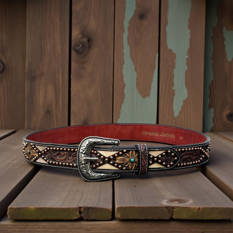 May include: A brown leather belt with a silver buckle and decorative floral and geometric patterns. The belt has turquoise accents and is 34 inches long.