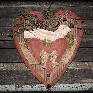 Könnte beinhalten: Ein herzförmiger Wandbehang aus Stoff mit einer weißen Taube, roten Beeren und einem braunen und weißen Streifenrand.