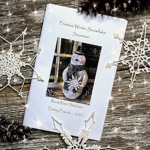 May include: A printable pattern for a primitive winter snowflake snowman. The pattern is titled "Primitive Winter Snowflake Snowman" and is by Rock River Stitches, Tammy Franck - 2024.