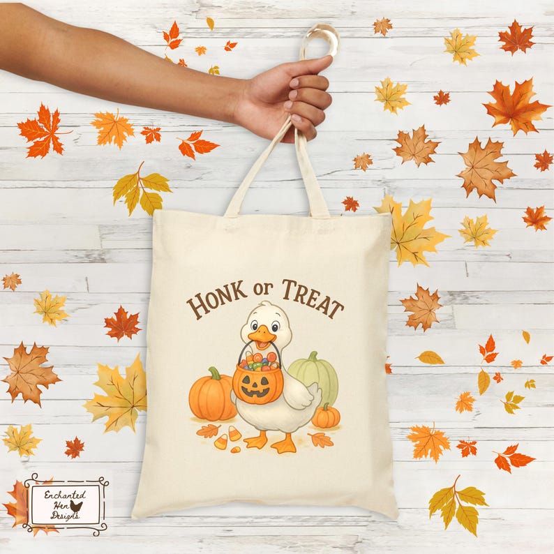 May include: Cream-colored tote bag with the text "Honk or Treat" and a cartoon duck holding a jack-o'-lantern bucket. The bag features pumpkins and candy corn, perfect for Halloween. The bag is held by a person's hand.