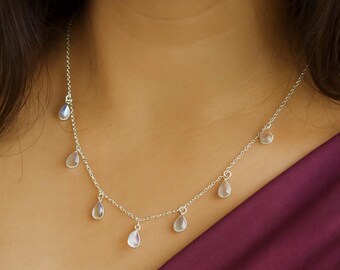 May include: A delicate silver necklace featuring multiple teardrop-shaped pendants. The necklace is worn around the neck, with the pendants hanging gracefully. The design is simple and elegant, suitable for everyday wear or special occasions.