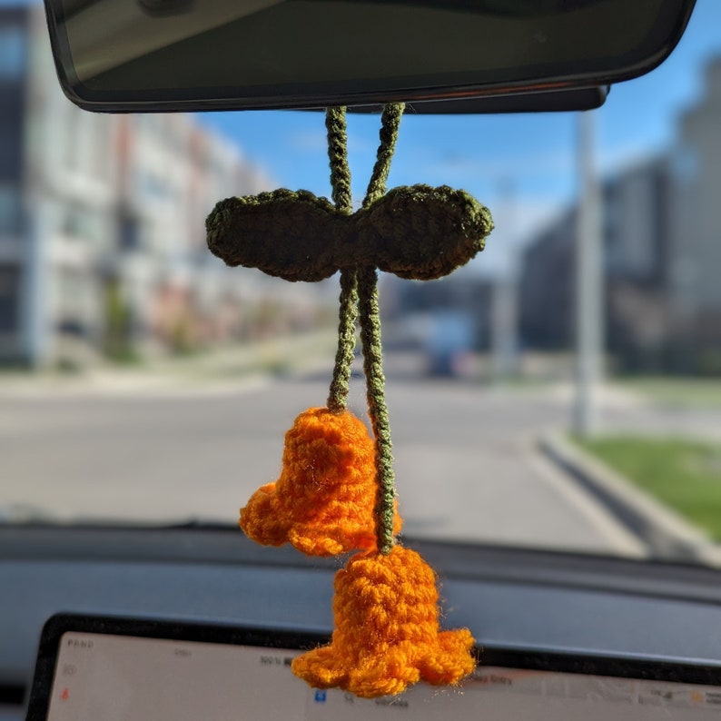 Orange lily of the valley charm hanging on rear-view mirror