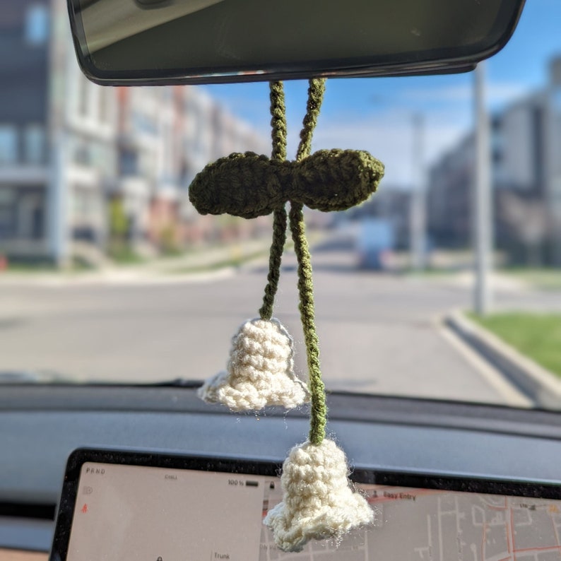 White lily of the valley charm hanging on rear-view mirror