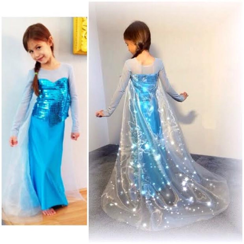 Puede incluir: Un disfraz de princesa azul y blanco con un corpi&ntilde;o brillante y una capa transparente con estrellas que se iluminan. El disfraz es perfecto para un disfraz de ni&ntilde;o o una fiesta con tem&aacute;tica de Frozen.