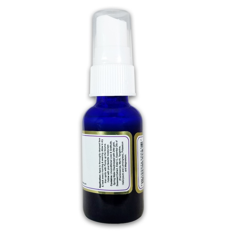 May include: A cobalt blue glass bottle with a white pump dispenser. The bottle has a gold label with white text detailing the product's application and ingredients, including gold, seaweed extract, and essential oils. The product is for the face and neck.